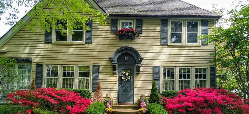 Clean home exterior with bright azaleas and fresh siding