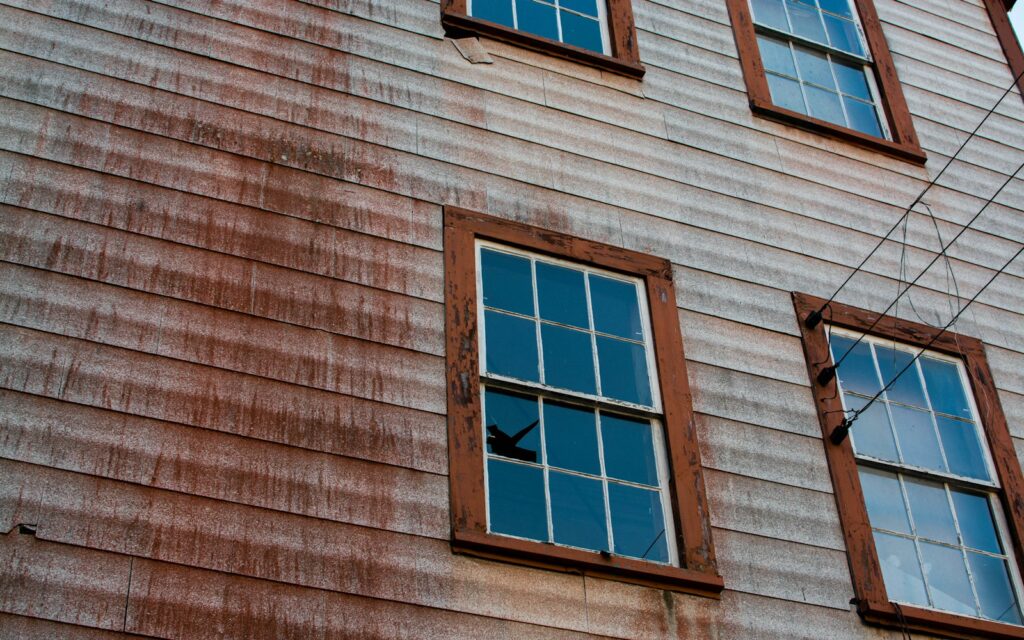 Weathered, stained wood siding on an older house that needs exterior cleaning