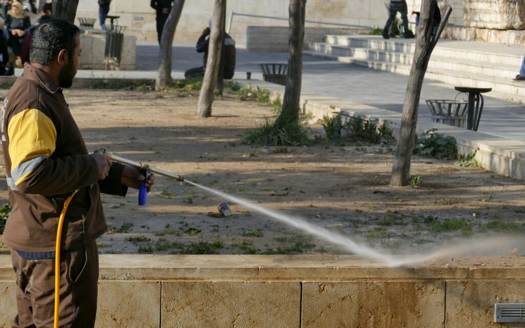 Worker using a pressure washer wand to clean an outdoor area